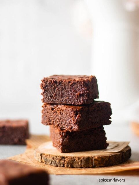 three pieces of stacked brownies placed on a wooden coaster