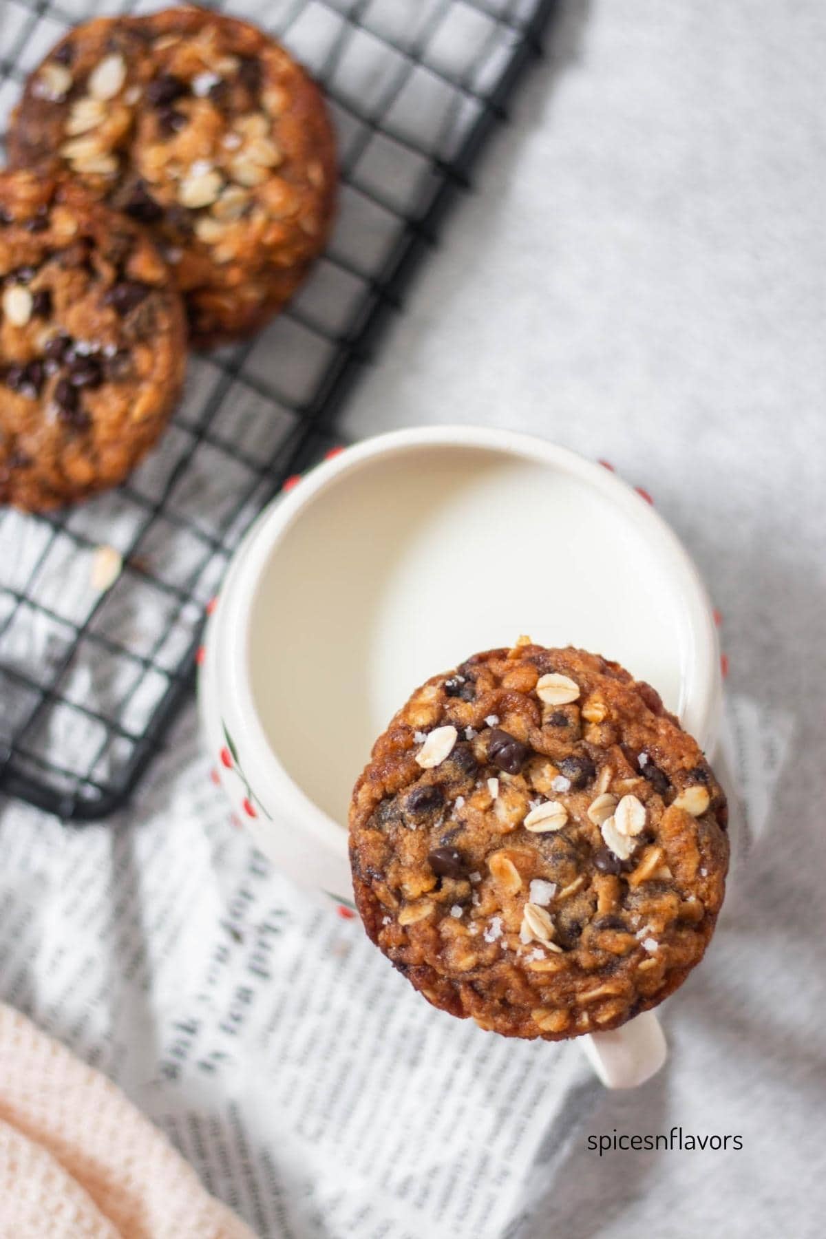 one oatmeal chocolate chip cookie placed on mug with milk