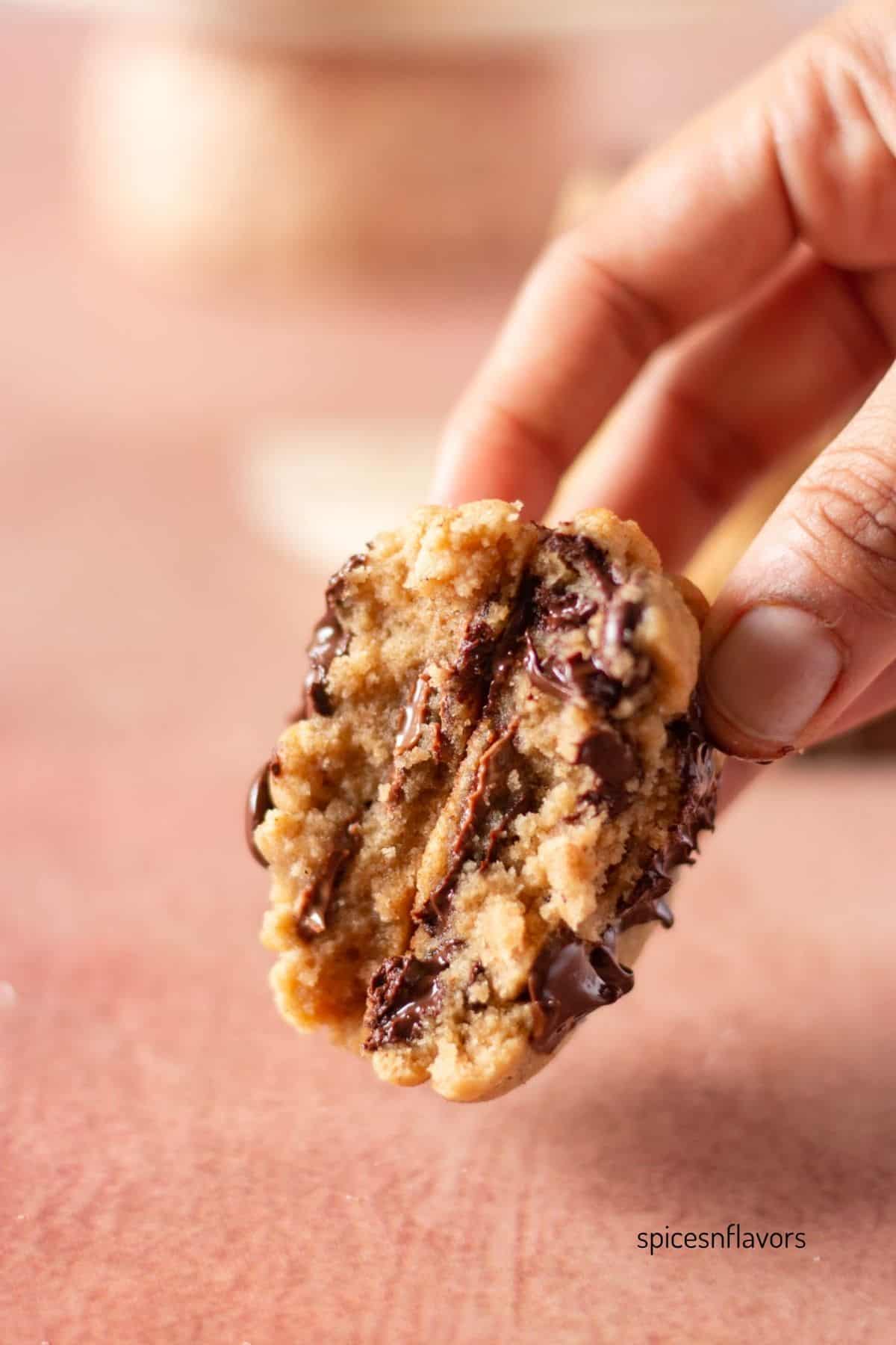 one chai chocolate chip cookie halved and held together showing the texture and thickness from within