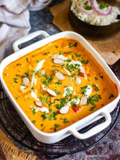mixed vegetable paneer curry served in a casserole garnished with almonds and cream