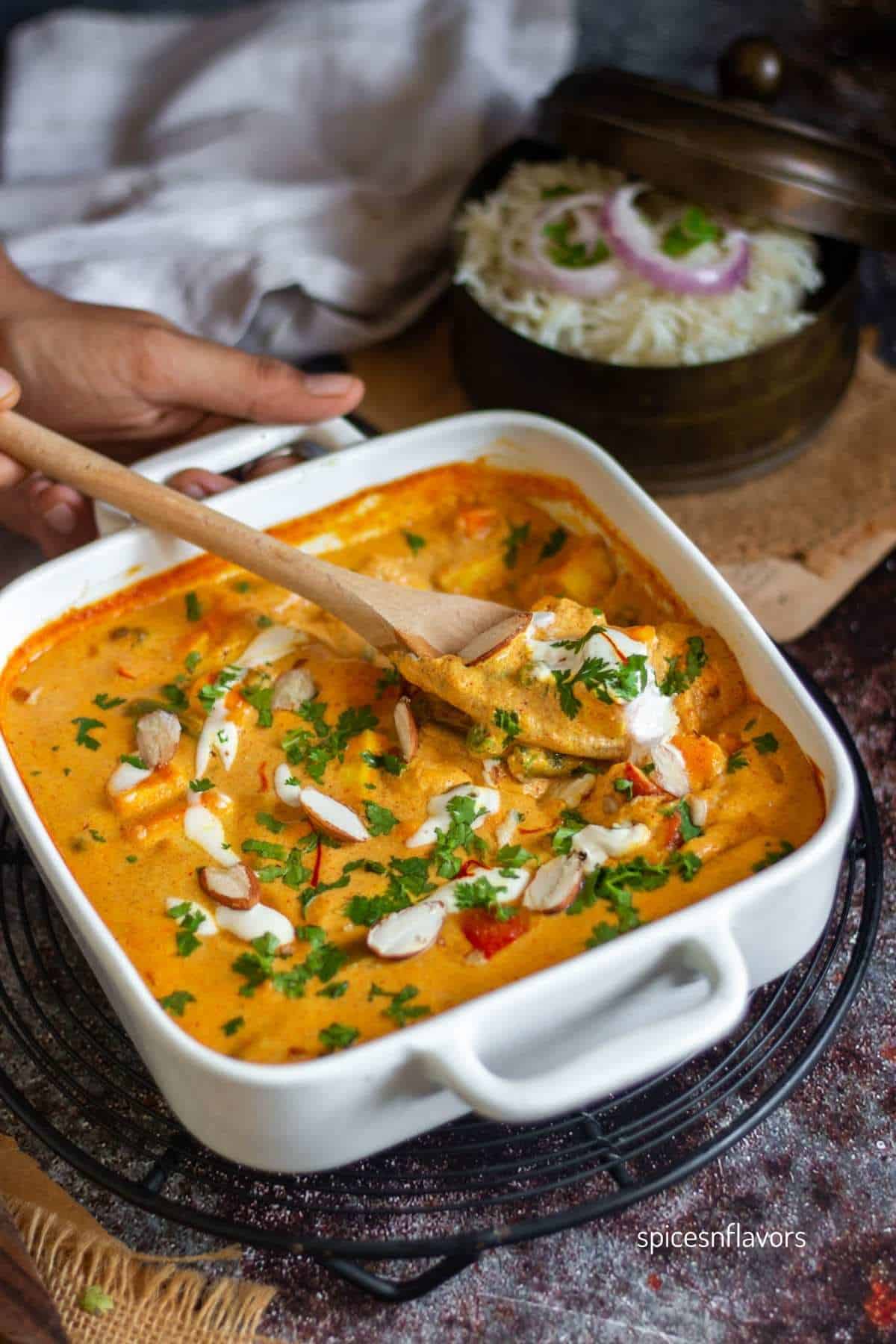 scooping paneer gravy with wooden spoon