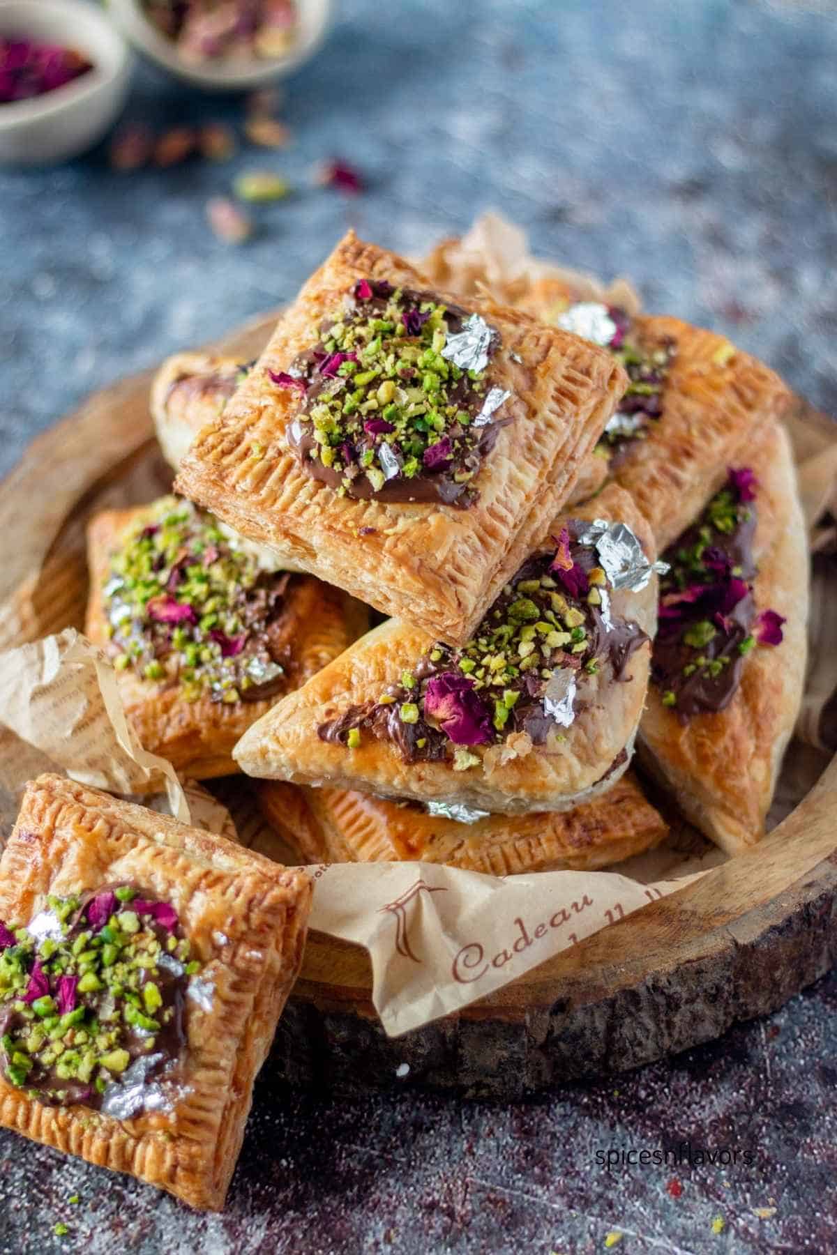 both puff squares and gujiyas placed on a wooden board