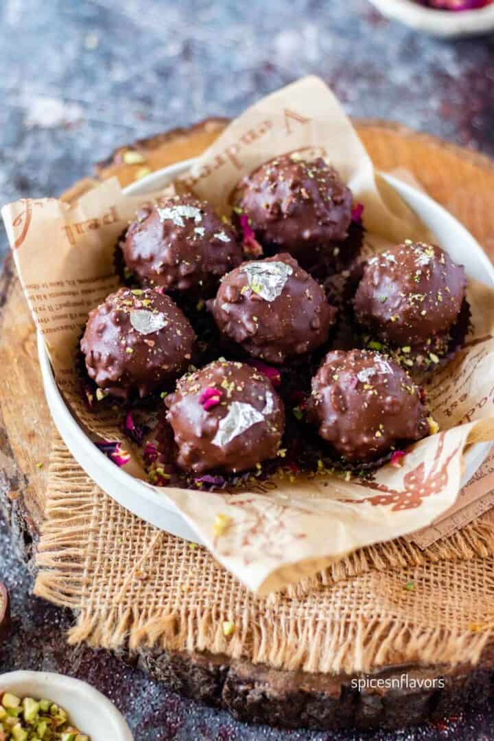 soan papdi truffles placed in a plate garnished with pistachios, varak and rose petals