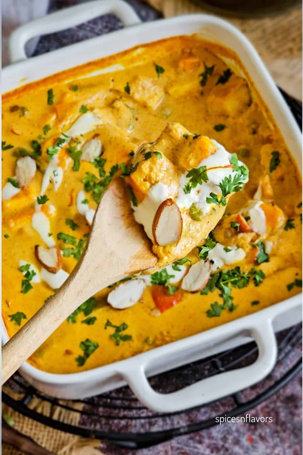 wooden spoon loaded with gravy, cream and sliced almonds