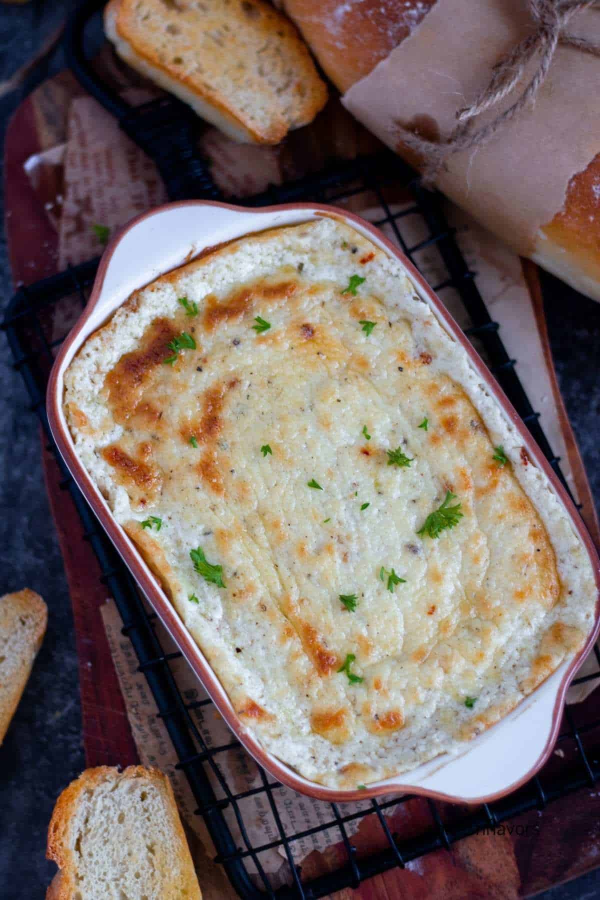 baked garlic bread dip in a casserole with bread kept on the sides