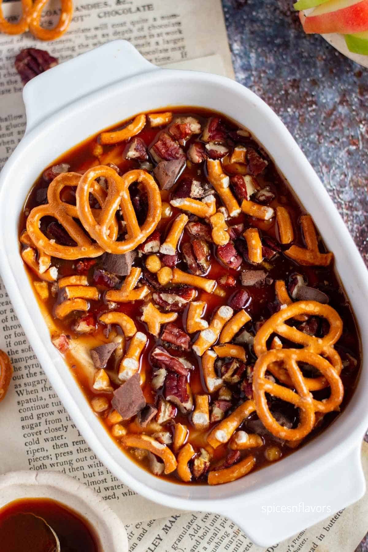 caramel apple dip placed in an oval dish with pretzel garnish