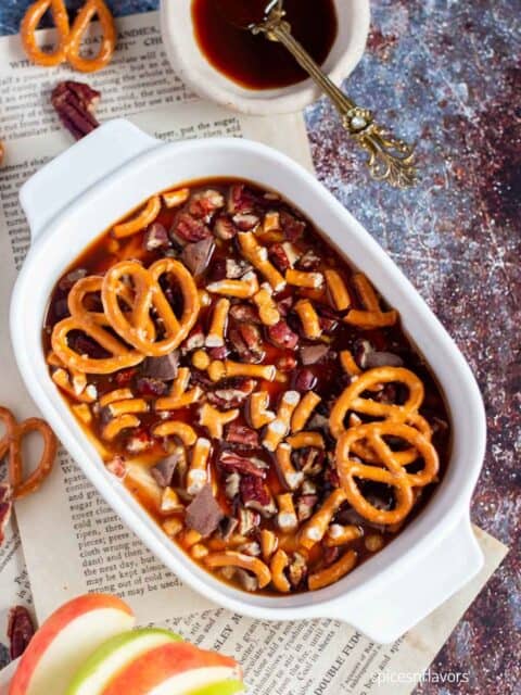caramel dip served in an oval white bowl with apples on the side
