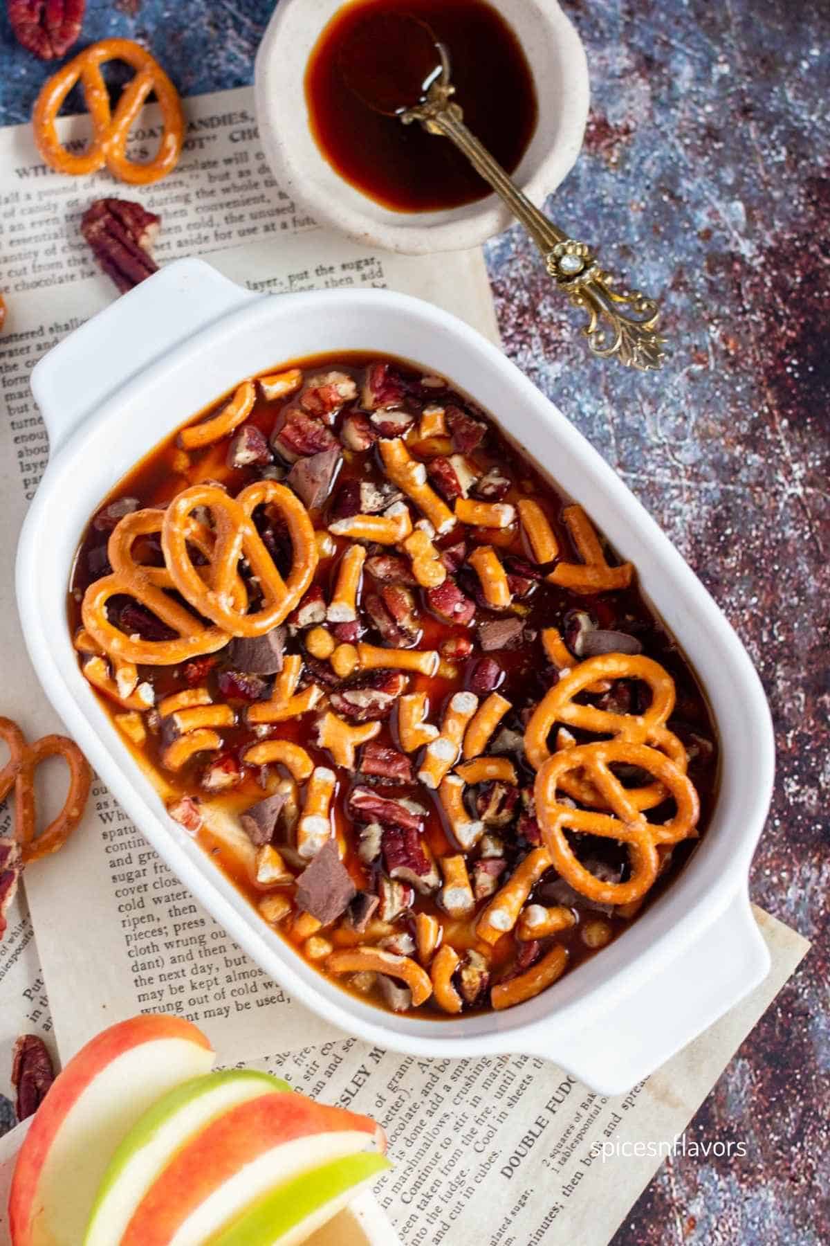 caramel dip served in an oval white bowl with apples on the side