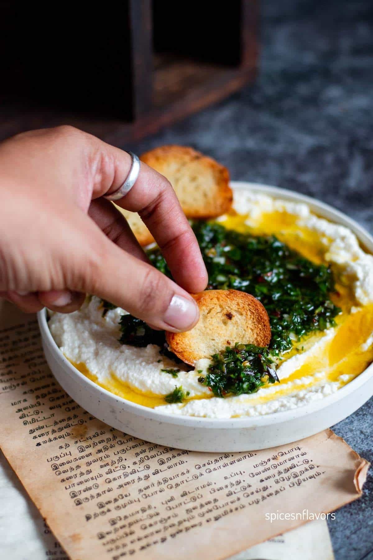 dipping mini baguette slice into the ricotta dip