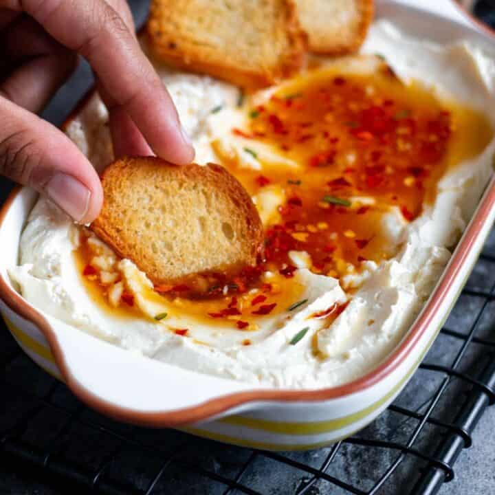 dipping bread in whipped feta dip with spicy honey