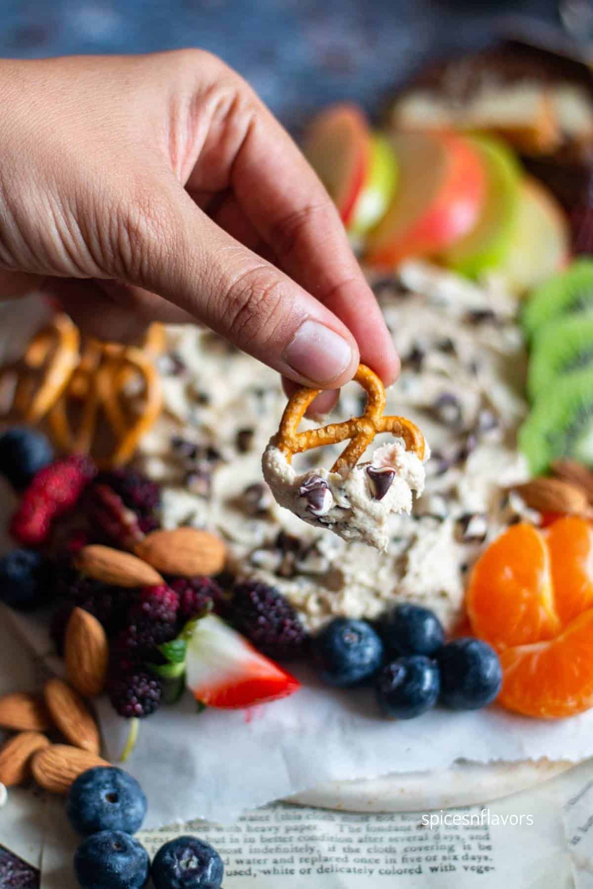 hand holding pretzel dipped in chocolate chip dip