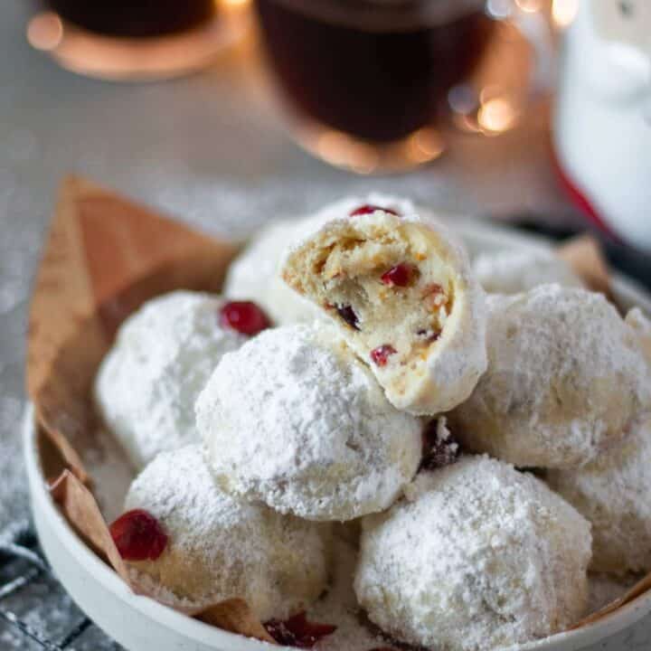 half eaten cranberry orange snowball cookies placed on a white plate