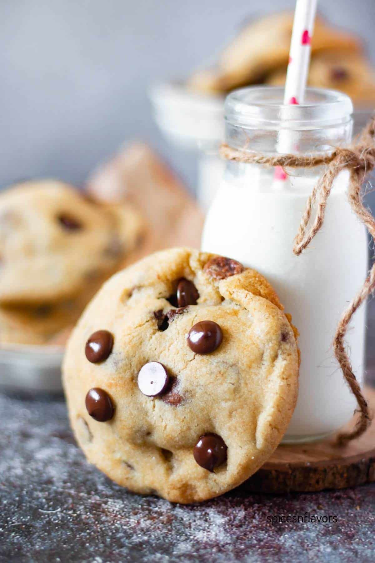 one oreo stuffed chocolate chip cookie placed against a bottle of milk