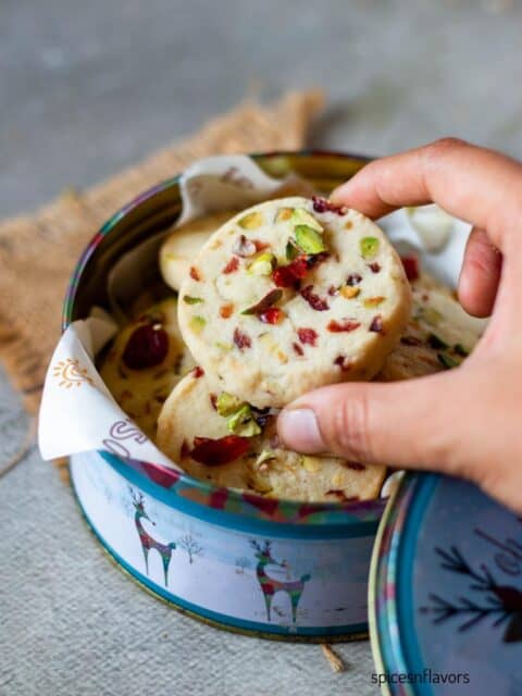picking up cranberry pistachios shortbread cookies from cookie tin