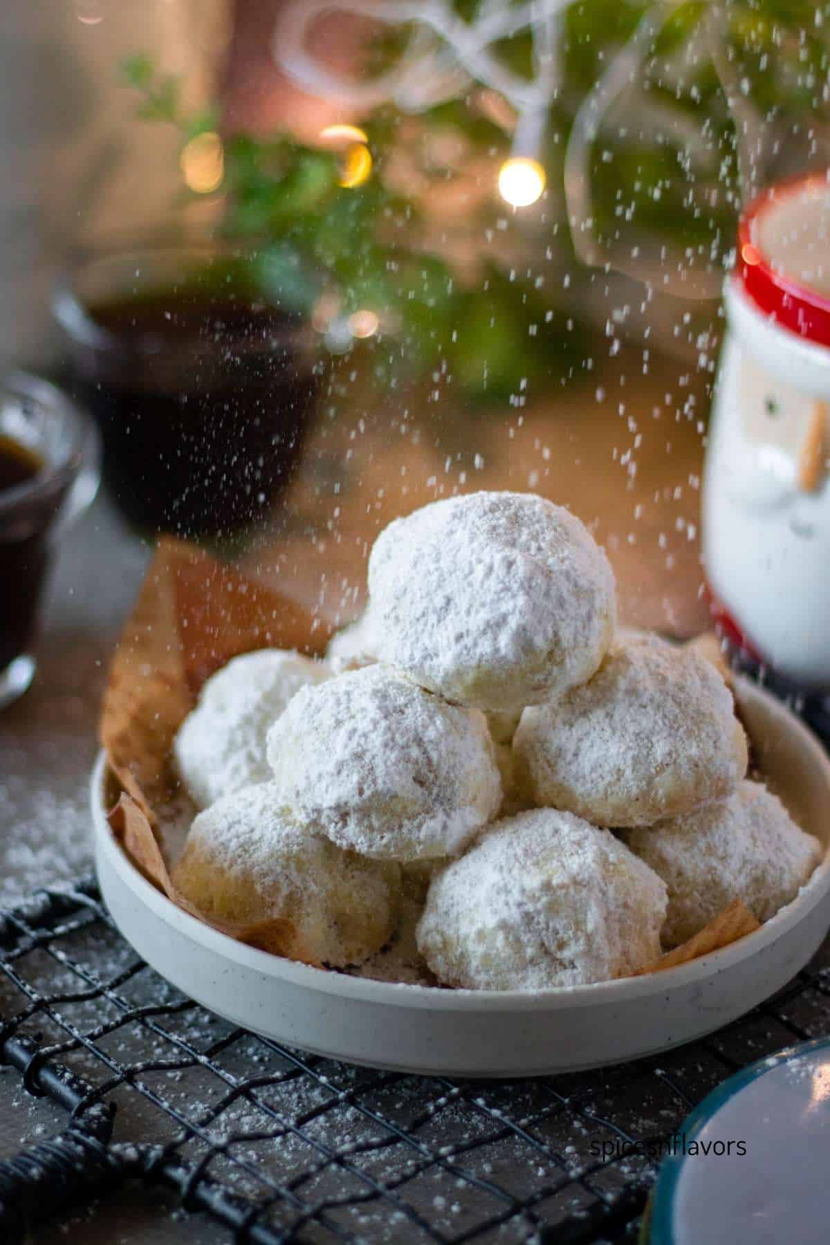 powdered sugar dusted on snowball cranberry cookies thats placed on a white plate