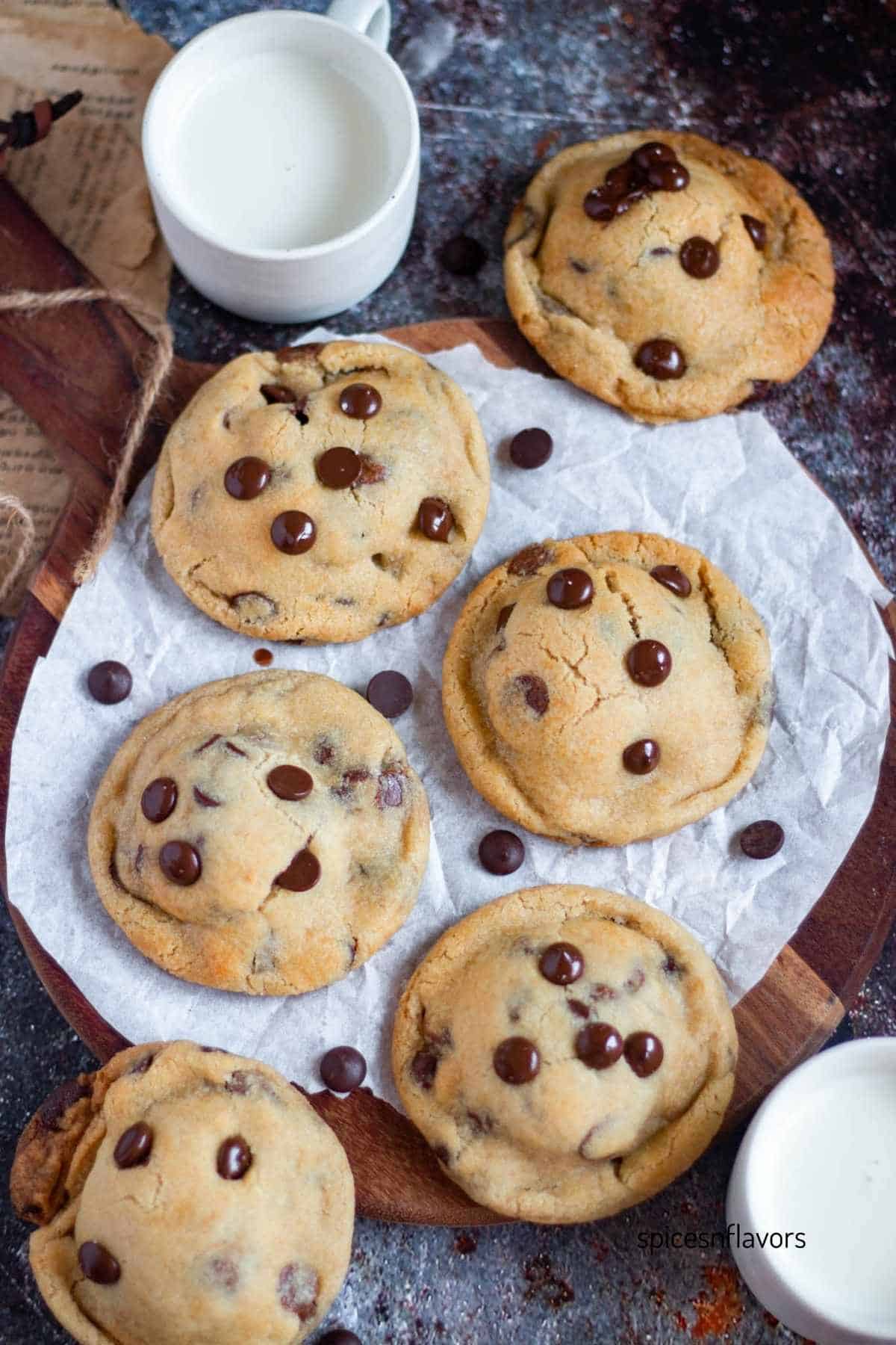 baked eggless oreo stuffed chocolate chip cookies on wooden board with two glasses of milk placed on the side
