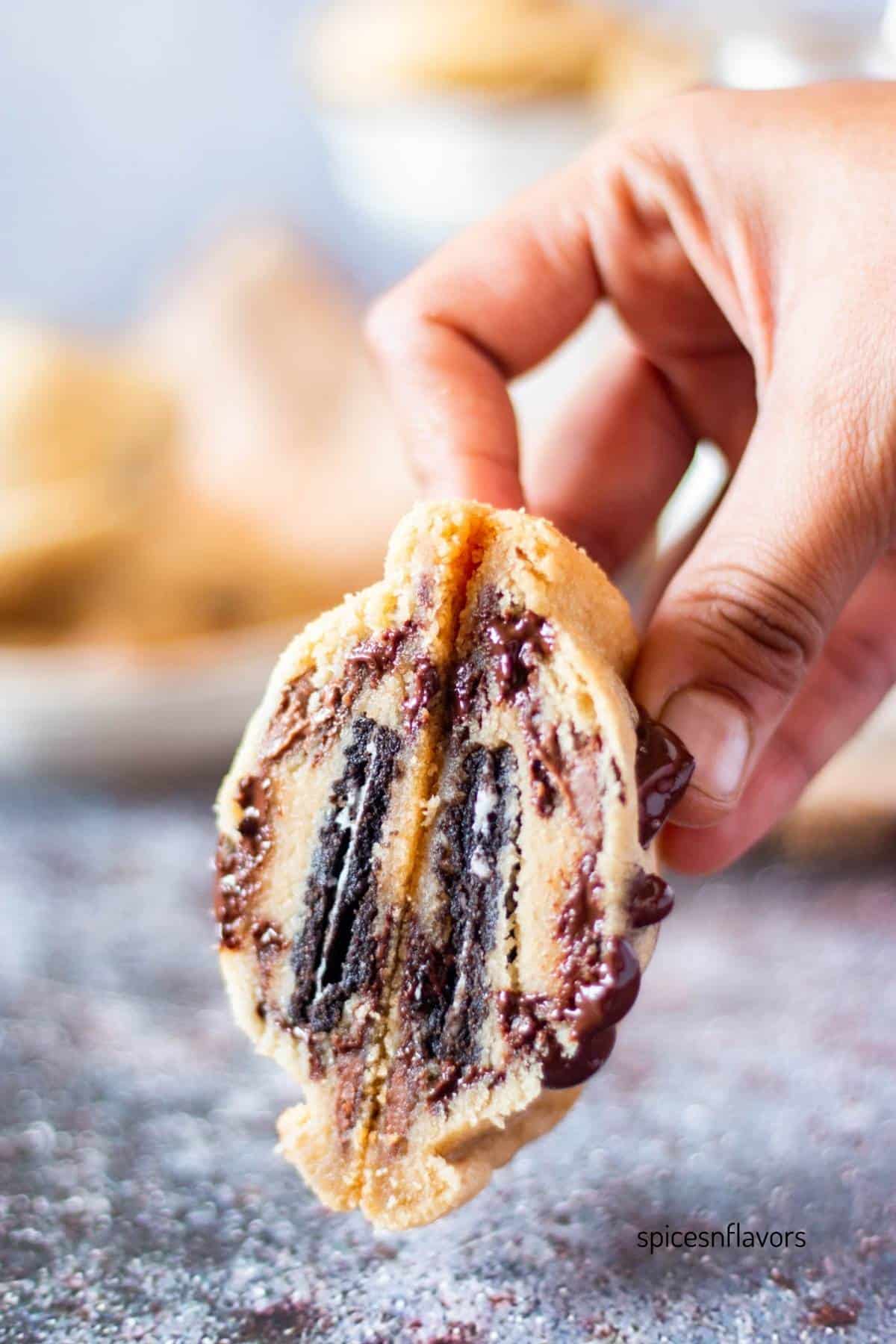 sliced eggless oreo stuffed chocolate chip cookie held in hand