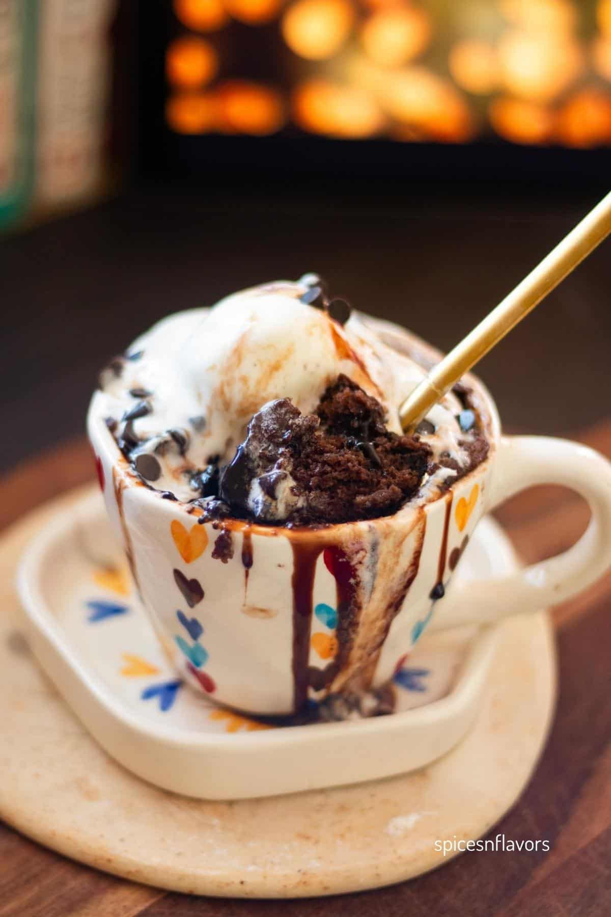 chocolate cake scooped out from the mug placed alongside the ice cream in the mug itself