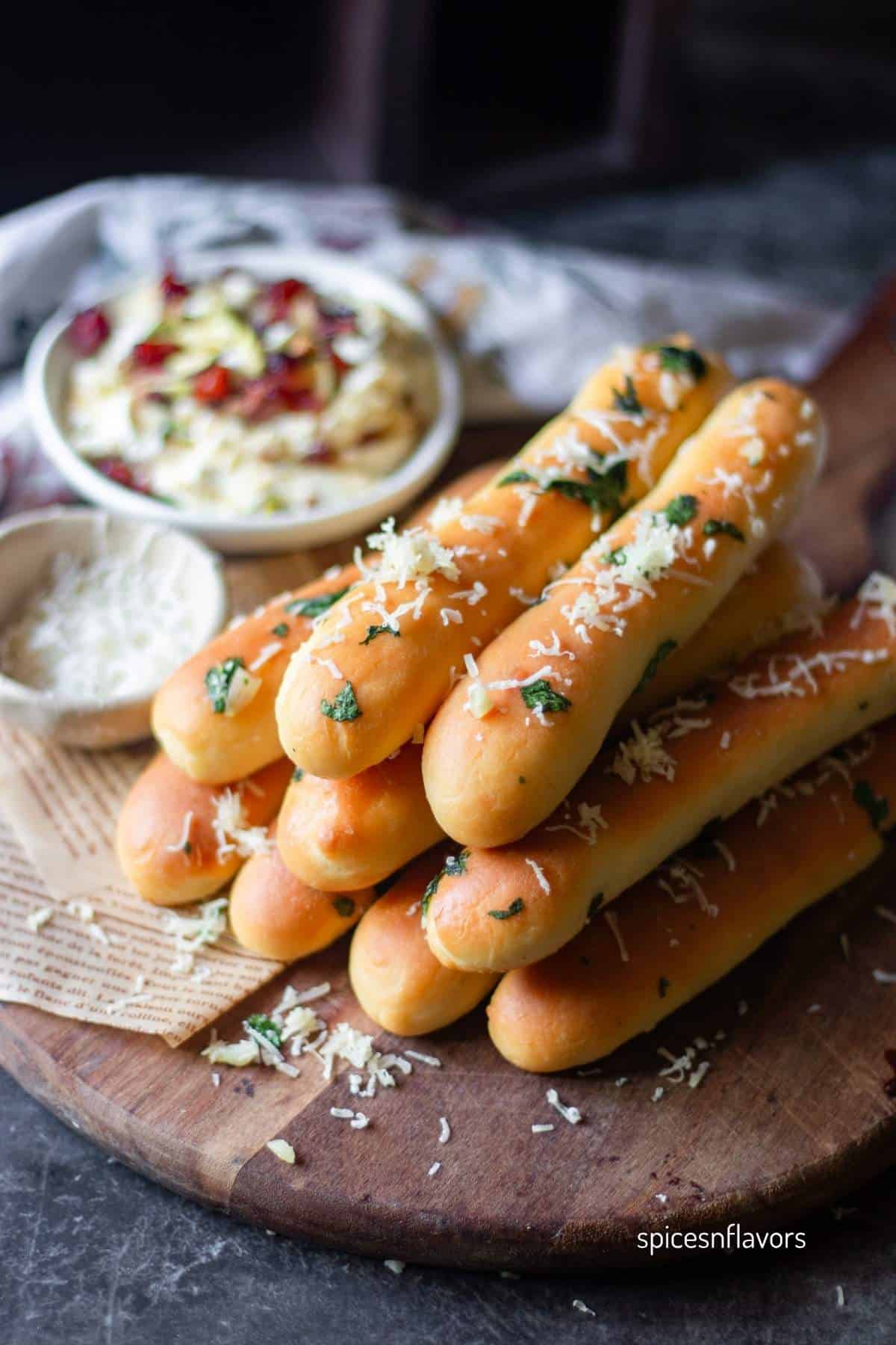 garlic breadsticks stacked on wooden board