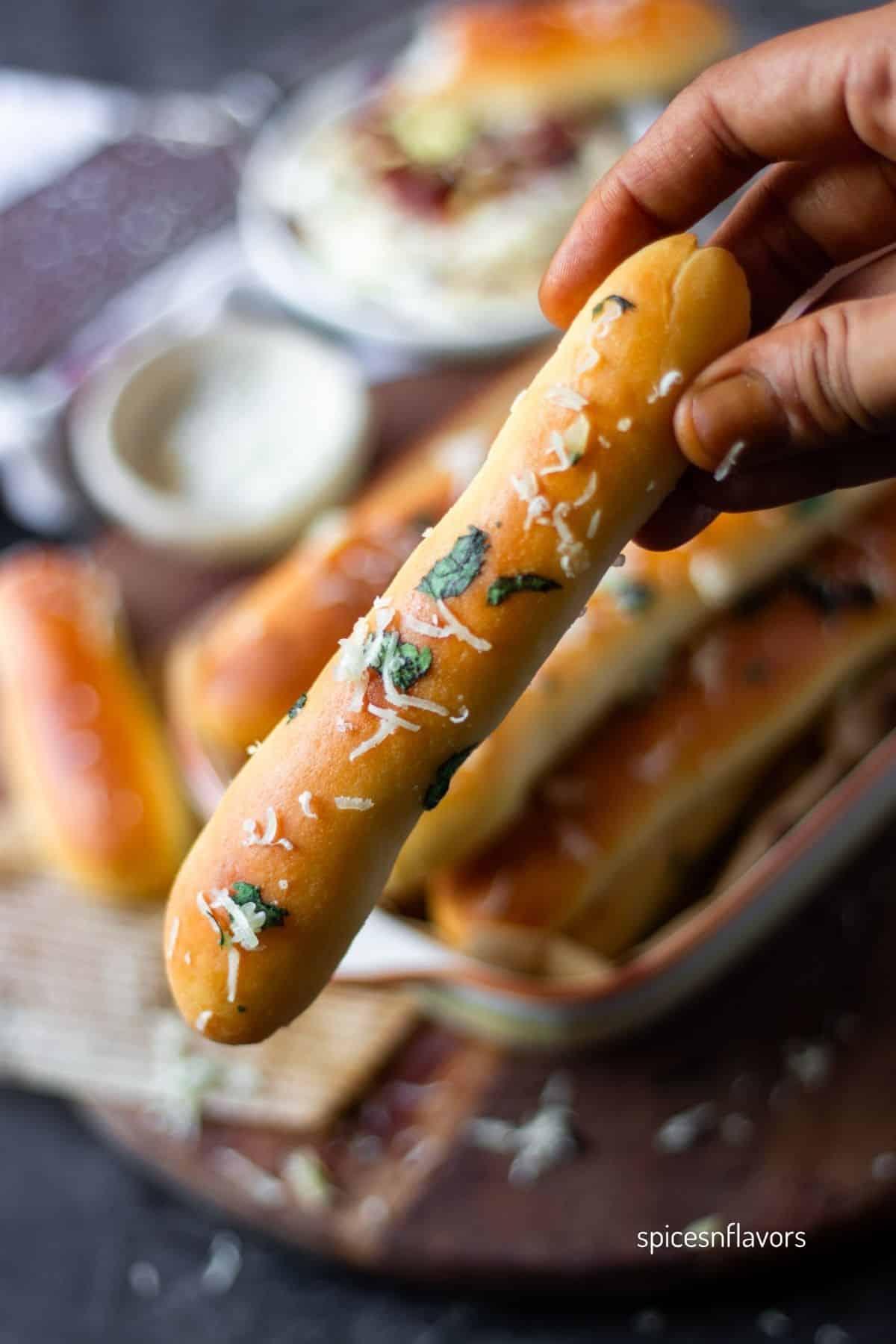 holding baked garlic breadsticks in your hand
